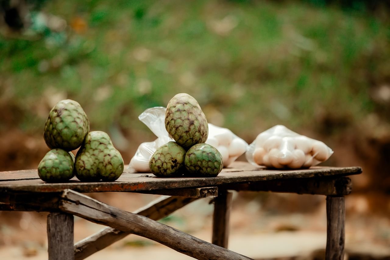 Close-up of cherimoya fruits arranged on a wooden table outdoors, offering a glimpse of natural abundance.